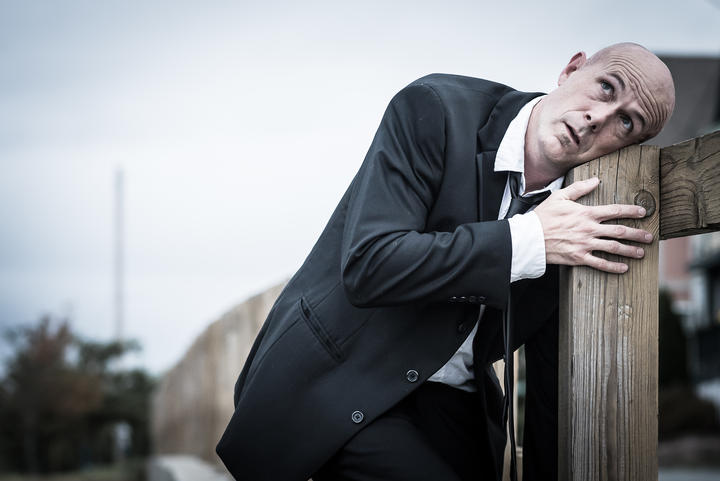 Andy Russ leans his head against a fencepost and stares thoughtfully up at the sky