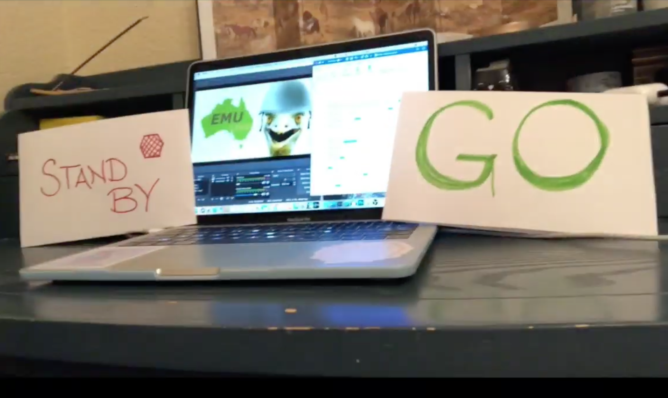 A laptop on a desk with hand drawn stop and go signs next to it